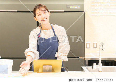 A young female store clerk providing guidance in front of the cash register 136674833