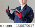 A middle-aged male businessman in work clothes holding a tablet and pointing his index finger up 136675037