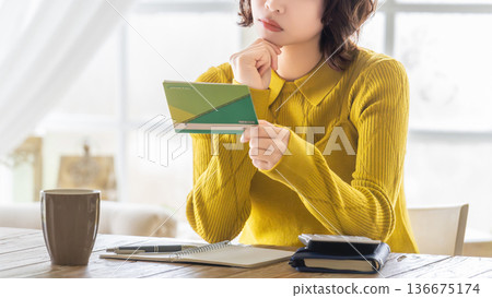 一位女士一邊看著存摺一邊思考 136675174