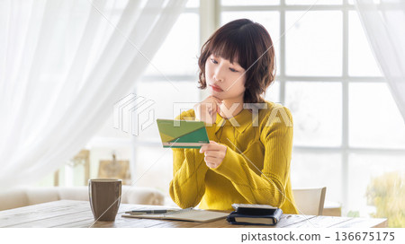 一位女士一邊看著存摺一邊思考 一位女士一邊看著存摺一邊思考 136675175