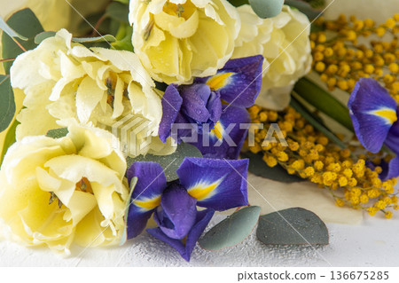 Spring bouquet of flowers. Irises, tulips, mimosa and eucalyptus. Yellow and blue flower. Bud close-up. Floral background. Purple iris, white double tulip. March mood. 136675285