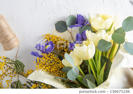 Spring bouquet of flowers. Irises, tulips, mimosa and eucalyptus. Yellow and blue flower. Bud close-up. Floral background. Purple iris, white double tulip. March mood. 136675286