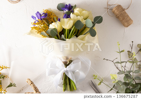 Spring bouquet of flowers. Irises, tulips, mimosa and eucalyptus. Yellow and blue flower. Bud close-up. Floral background. Purple iris, white double tulip. March mood. 136675287