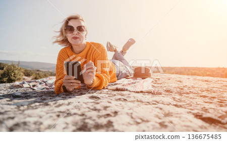 Young Woman Relaxing on a Rock Cliff with Phone and Blanket Young Woman Relaxing on a Rock Cliff with Phone and Blanket 136675485