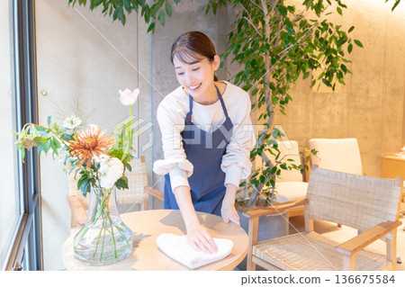 A young female waitress wiping the tables at a cafe A young female waitress wiping the tables at a cafe 136675584