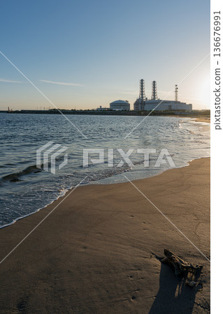 黃昏時分,靜謐的沙灘和海岸線旁的火力發電廠。 黃昏時分,靜謐的沙灘和海岸線旁的火力發電廠。 136676991