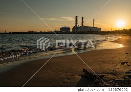 Quiet sandy beach at dusk and a thermal power plant along the coast Quiet sandy beach at dusk and a thermal power plant along the coast 136676992
