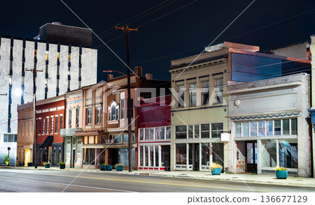 Historic storefronts on North State Street in Jackson, Mississippi. A row of vintage commercial buildings with colorful brick facades and decorative cornices is illuminated by streetlights at night 136677129
