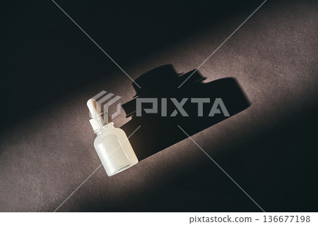 Skincare serum dropper bottle casting shadow on dark background Skincare serum dropper bottle casting shadow on dark background 136677198