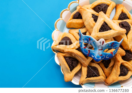 Composition with carnival mask, Hamantaschen cookies and rattle for Purim holiday on color background Composition with carnival mask, Hamantaschen cookies and rattle for Purim holiday on color background 136677280
