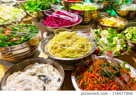 A colorful assortment of fresh vegetable salads, including tomatoes, cucumbers, carrots, and cabbage, are arranged in salad bowls on the buffet table. A colorful assortment of fresh vegetable salads, including tomatoes, cucumbers, carrots, and cabbage, are arranged in salad bowls on the buffet table. 136677866