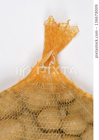 Raw potatoes in a yellow mesh bag Raw potatoes in a yellow mesh bag 136678009