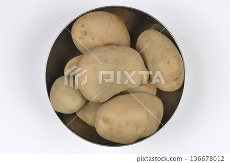 Raw potatoes in a metal bowl on white background Raw potatoes in a metal bowl on white background 136678012