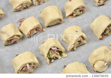 Raw yeast rolls with prosciutto and herbs on baking paper 136678030