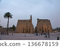 The First Pylon of the Luxor Temple in Egypt. Illuminated obelisk and Colossus of Ramses II 136678159