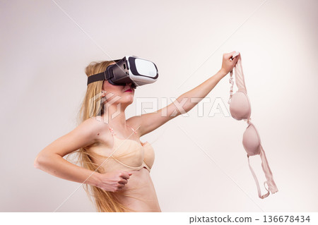 Girl in virtual reality goggles holds bra 136678434