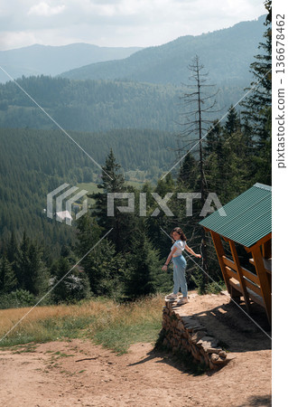 Young woman enjoying mountain landscape near wooden cabin 136678462