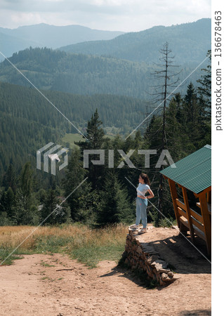 Young woman enjoying mountain landscape near wooden cabin Young woman enjoying mountain landscape near wooden cabin 136678463