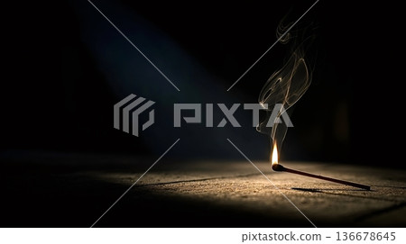 Single burning matchstick lighting dark background with smoke 136678645