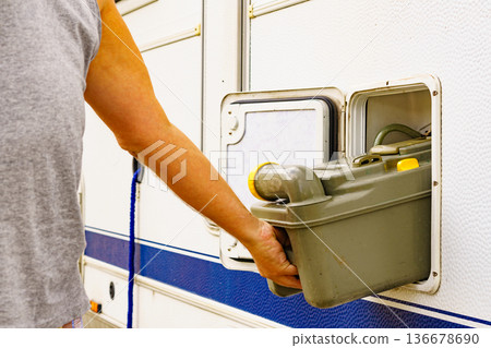 Man serving caravan, tank toilet cassette in dump station. 136678690