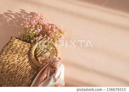 Woven Straw Handbag with Silky Scarf and Flowers. Elegant Summer Fashion Flatlay on Peach Background 136679315
