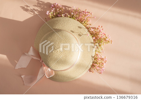 Straw Hat with Pink Ribbon and Flowers. Romantic Spring Summer Flatlay on Peach Background 136679316