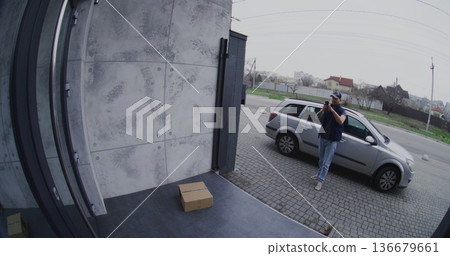 Courier in Silver Car Places Parcel on Porch and Takes Smartphone Photo For Confirmation Courier in Silver Car Places Parcel on Porch and Takes Smartphone Photo For Confirmation 136679661