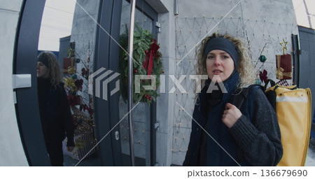 Courier With Large Delivery Backpack Arrives at House and Rings Doorbell 136679690
