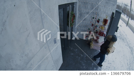 Female Passerby Approaches Festively Decorated House, Notices Parcel on Porch, Quickly Picks it Up Female Passerby Approaches Festively Decorated House, Notices Parcel on Porch, Quickly Picks it Up 136679706