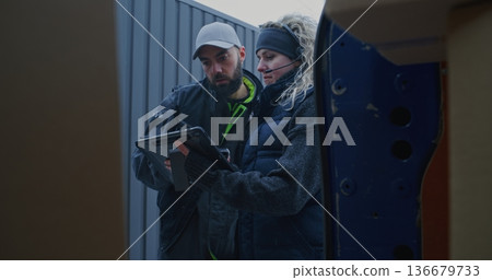 Man Moves Parcels From Pallet Jack Into Blue Van While Woman Scans Barcodes and Checks Tablet Man Moves Parcels From Pallet Jack Into Blue Van While Woman Scans Barcodes and Checks Tablet 136679733