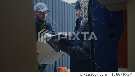Man Moves Parcels From Pallet Jack Into Blue Van While Woman Scans Barcodes and Checks Tablet Man Moves Parcels From Pallet Jack Into Blue Van While Woman Scans Barcodes and Checks Tablet 136679737