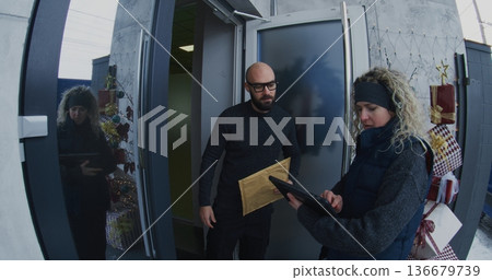 Professional Female Courier Hands Over Large Document Envelope to Man at Front Door Professional Female Courier Hands Over Large Document Envelope to Man at Front Door 136679739