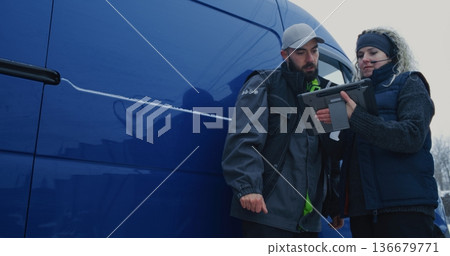 Courier Moves Cardboard Boxes Inside Blue Van While Colleague Scans Barcodes Using Tablet Courier Moves Cardboard Boxes Inside Blue Van While Colleague Scans Barcodes Using Tablet 136679771