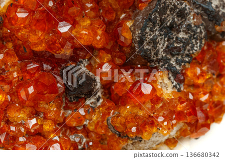 macro mineral stone Spessartine, orange, red garnet with quartz on white background 136680342
