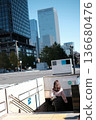 Asian businesswoman in a light pink blouse walking down the entrance of a Tokyo Metro subway station in the Marunouchi business district, Japan 136680476