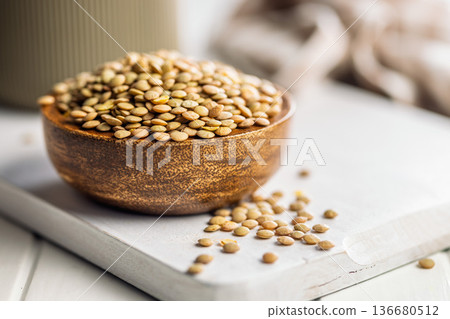 Uncooked green lentil in bowl on white table. Uncooked green lentil in bowl on white table. 136680512