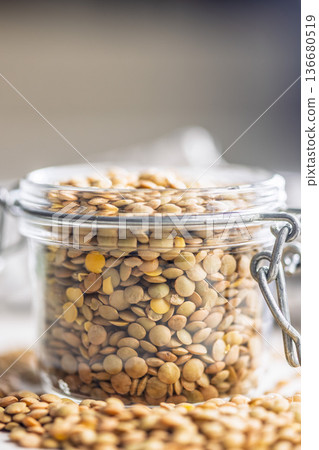 Uncooked green lentil in jar on white table. Uncooked green lentil in jar on white table. 136680519