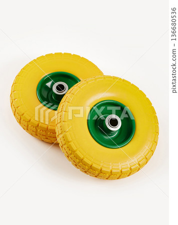 Two wheels from a garden cart on a white background. Yellow rubber, green disc. 136680536