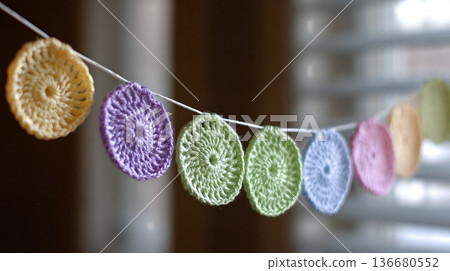 Crochet Garland Hangs in a Room With Soft Light From a Window During a Quiet Afternoon Crochet Garland Hangs in a Room With Soft Light From a Window During a Quiet Afternoon 136680552