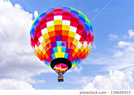 Colorful hot air balloon flying over blue sky with white clouds Colorful hot air balloon flying over blue sky with white clouds 136680935