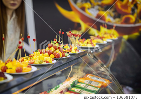 Cheese cubes with cherry tomatoes and olives served on plates with skewers on supermarket tasting counter. Concept of food sampling, cheese appetizers, retail promotion marketing 136681073