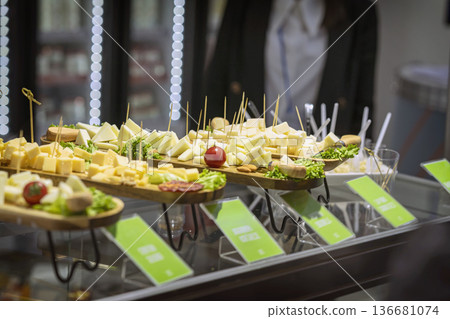 Cheese platter with assorted cheese cubes and slices served on wooden boards at buffet table. Concept of cheese tasting, catering event, gourmet snack, hospitality service, food sampling event Cheese platter with assorted cheese cubes and slices served on wooden boards at buffet table. Concept of cheese tasting, catering event, gourmet snack, hospitality service, food sampling event 136681074
