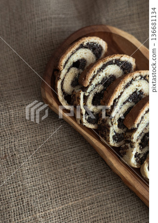 Homemade poppy seed cake slices arranged neatly on long wooden board with burlap underneath Homemade poppy seed cake slices arranged neatly on long wooden board with burlap underneath 136681134