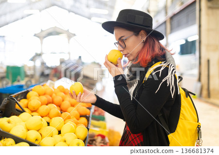 Woman smelling fresh yellow apple at market 136681374