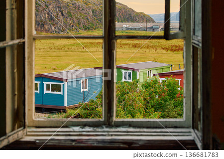 Weathered wooden houses in Teriberka at dusk, Russia, Kola Peninsula, evoke a bygone era, standing as silent witnesses to the passage of time. Teriberka's historical architecture concept 136681783
