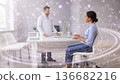 Doctor consulting a patient in a modern clinic with glowing digital energy effects and sparkles. 136682216