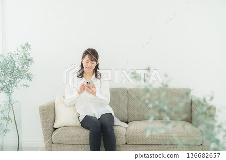 A woman looking at her smartphone in the living room 136682657