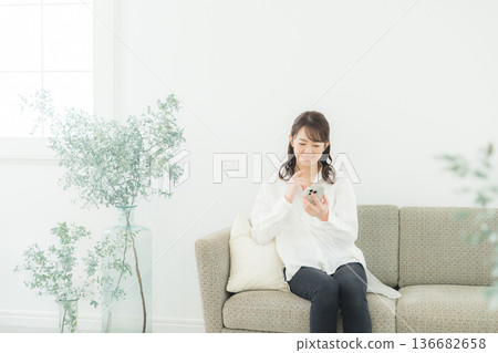 A woman looking at her smartphone in the living room A woman looking at her smartphone in the living room 136682658