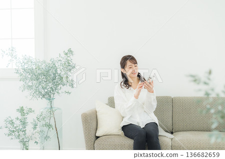一個女人在客廳裡看著她的智能手機 一個女人在客廳裡看著她的智能手機 136682659