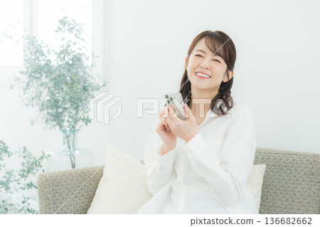 A woman looking at her smartphone in the living room 136682662